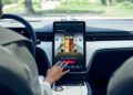 A person interacts with a large touchscreen display in a Volvo EX90, using navigation or media controls while parked in the modern SUV.