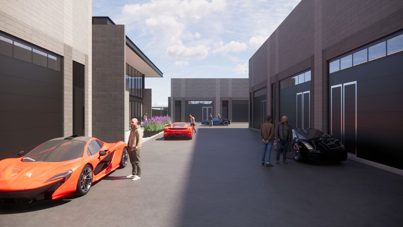 Several people stand near luxury sports cars in a modern, open courtyard with industrial-style buildings under a partly cloudy sky.