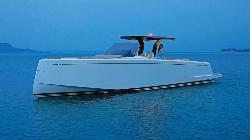 A modern white motor yacht with a streamlined design floats on calm blue water, offering a true maritime experience as a person sits at the helm under a small roof. Explore more luxury yachts like this among our yachts for sale.