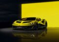 A yellow Lamborghini Centro Stile at 20 is parked indoors in front of a large illuminated yellow background, with its reflection visible on the glossy floor, celebrating the studio behind every modern bull.