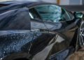 Close-up of a black Lamborghini sports car with metallic paint, showing reflections of clouds and sunlight on the angled body and windows—a striking choice among car colors that highlights its modern origins.