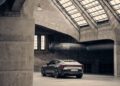 A sleek, gray Polestar 5 electric car is parked inside a spacious, industrial-style building with concrete walls and large skylights—perfect for a film set starring Alexander Skarsgård.