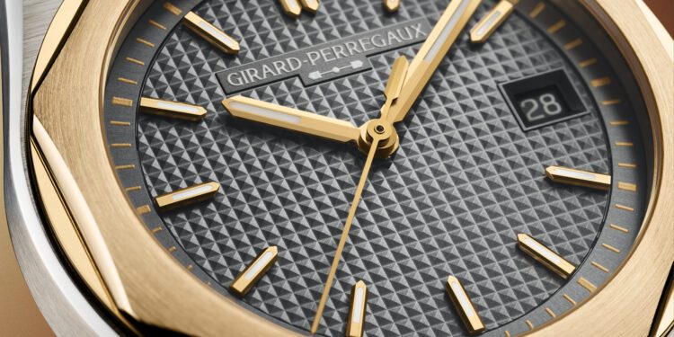 Close-up of a Girard-Perregaux Laureato FIFTY wristwatch featuring a textured black dial, gold hour markers and hands, a date window showing "28," and a gold and steel bezel.