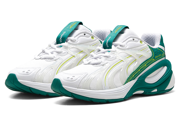 A pair of white athletic sneakers with green and yellow accents, thick soles, and mesh uppers from the PUMA Motorsport F1 Team Collection, displayed side by side.