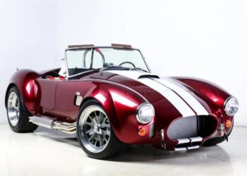 A classic red Shelby Cobra sports car with white racing stripes, chrome side pipes, and silver wheels—this unique creation is photographed in a studio with a white background, ready to make a statement in any garage.