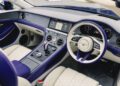 Luxury car interior featuring cream and Violette Color leather seats, a digital dashboard, touchscreen display, and Bentley logo on the steering wheel—exuding the signature elegance of the Continental GTC Speed.