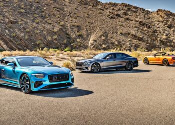 Three luxury cars—a blue coupe, a silver sedan, and an orange convertible—stand on a paved desert road as the First Ombré by Mulliner Collection arrives at Bentley Rancho Mirage with three bespoke commissions.