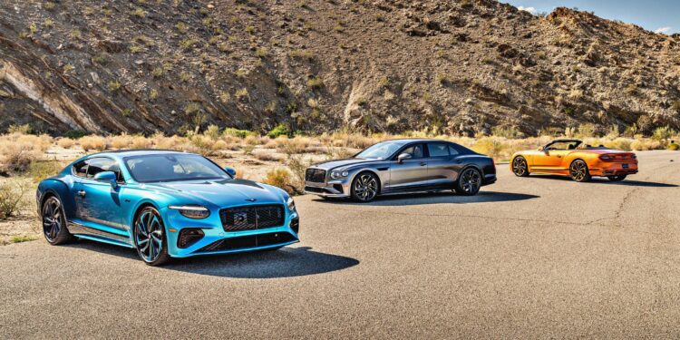 Three luxury cars—a blue coupe, a silver sedan, and an orange convertible—stand on a paved desert road as the First Ombré by Mulliner Collection arrives at Bentley Rancho Mirage with three bespoke commissions.