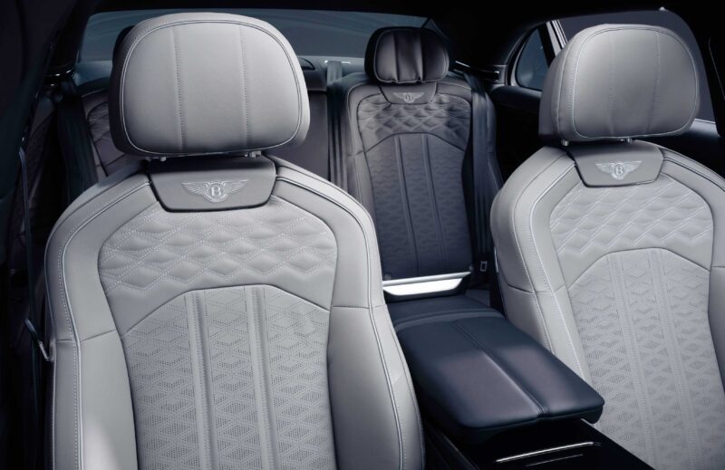 Close-up view of the front and rear seats inside a Bentley, featuring light gray quilted leather upholstery and embossed Bentley logos—part of the First Ombré by Mulliner Collection arriving at Bentley Rancho Mirage with three bespoke commissions.
