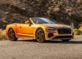 A gold convertible luxury sports car, from the First Ombré by Mulliner Collection, is parked on a paved road with rocky terrain and dry vegetation—one of three bespoke commissions arriving at Bentley Rancho Mirage.