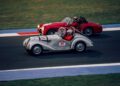 Two people drive a white vintage race car marked with the number 24 alongside a red number 23 car on the Modena Cento Ore racetrack, celebrating the event's 25th Anniversary from Oct. 5-10.