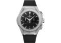 A Hublot wristwatch with a geometric silver case, black dial, white markers, and chronograph subdials, featuring a black rubber strap—an exemplary choice among the best luxury watches.