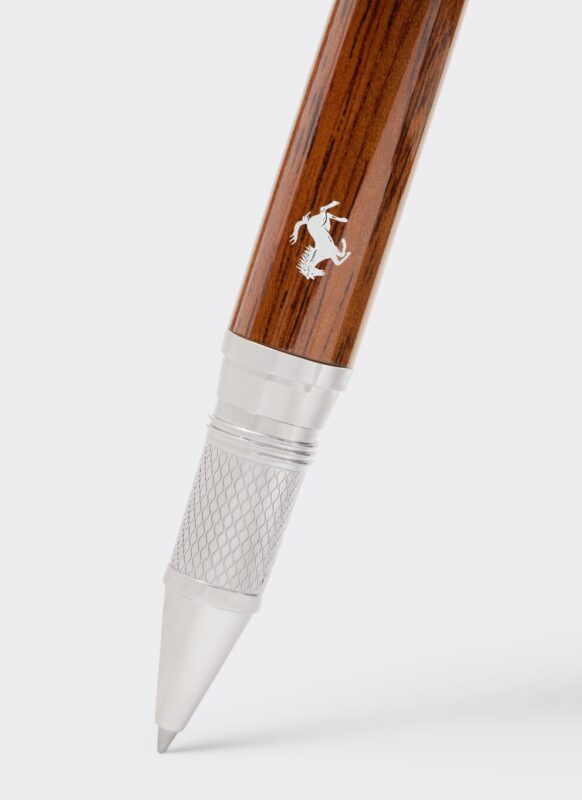 A close-up of a luxury Meisterstück pen with a wooden barrel, silver grip, and a silver animal logo near the tip, positioned against a plain background.