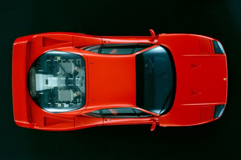 Top view of a red sports car with a transparent engine cover, revealing the engine components inside—a detail often highlighted in discussions like Comparison: Ferrari F40 Vs Ferrari F50.