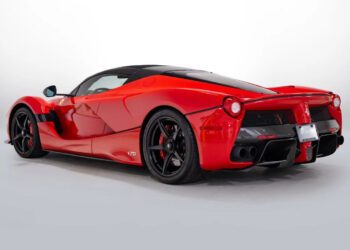 A red sports car with black accents, reminiscent of the Most Expensive Ferraris, is shown from the rear three-quarter angle against a plain white background.