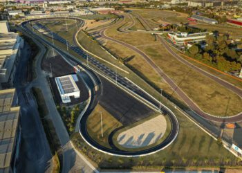 Aerial view of the Ferrari e-Vortex Test Track, a large, winding test track with multiple curves and paved roads, surrounded by grassy areas and nearby buildings.