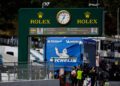 A large Rolex clock and leaderboard overlook the Petit Le Mans racetrack, with the Michelin logo in the background and crowds gathering near race cars and pit stations.