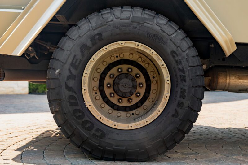 Close-up view of a Goodyear G275 MSA tire mounted on a beige metal wheel of a street-legal Terradyne Gurkha, showing the tread and wheel bolts.