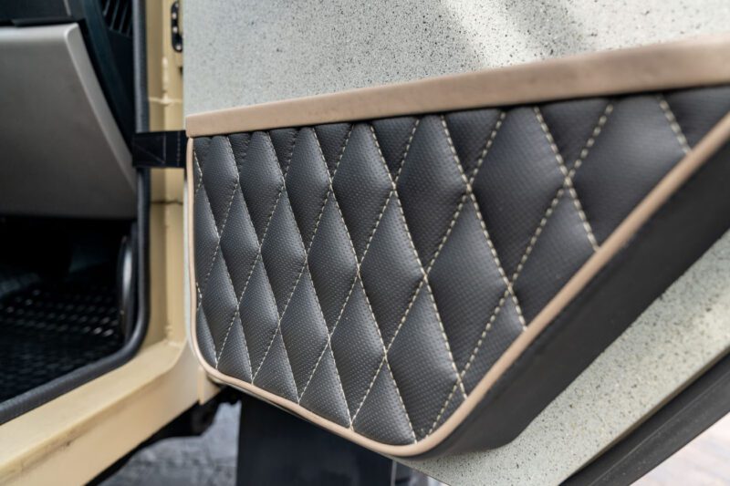Close-up of a car door interior featuring diamond-stitched black leather upholstery with beige trim and visible stitching detail, showcasing the premium craftsmanship found in every Terradyne Gurkha for sale.