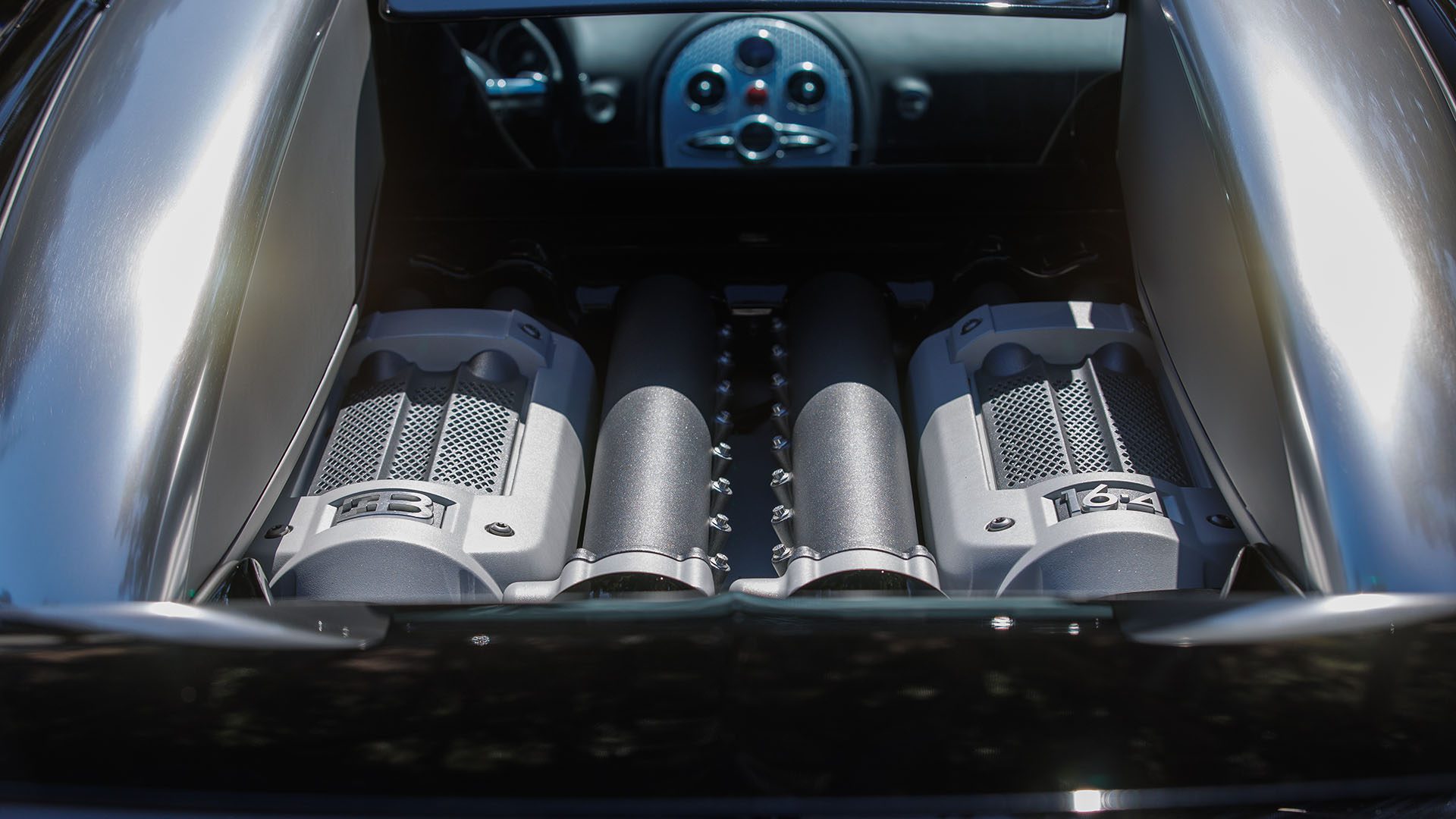 Close-up view of a Bugatti Veyron engine at Broad Arrow’s Las Vegas 2025 event, highlighting the dual air intakes and metallic engine covers with "EB" and "16.4" branding.