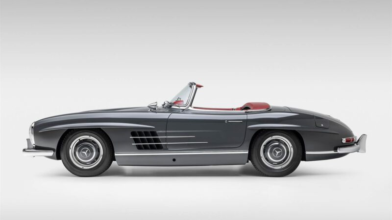 Side view of a classic black convertible car with a red interior, featuring chrome details, reminiscent of the 2009 Mercedes-Benz SLR McLaren, against a plain light background. Showcased at Broad Arrow Las Vegas 2025.