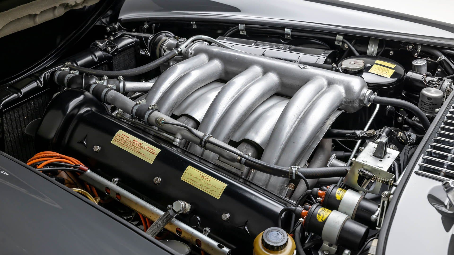 Close-up view of a clean, classic Mercedes-Benz SLR McLaren engine compartment featuring a large silver intake manifold, various hoses, and labeled components—set to dazzle at Broad Arrow’s Las Vegas 2025 auction.