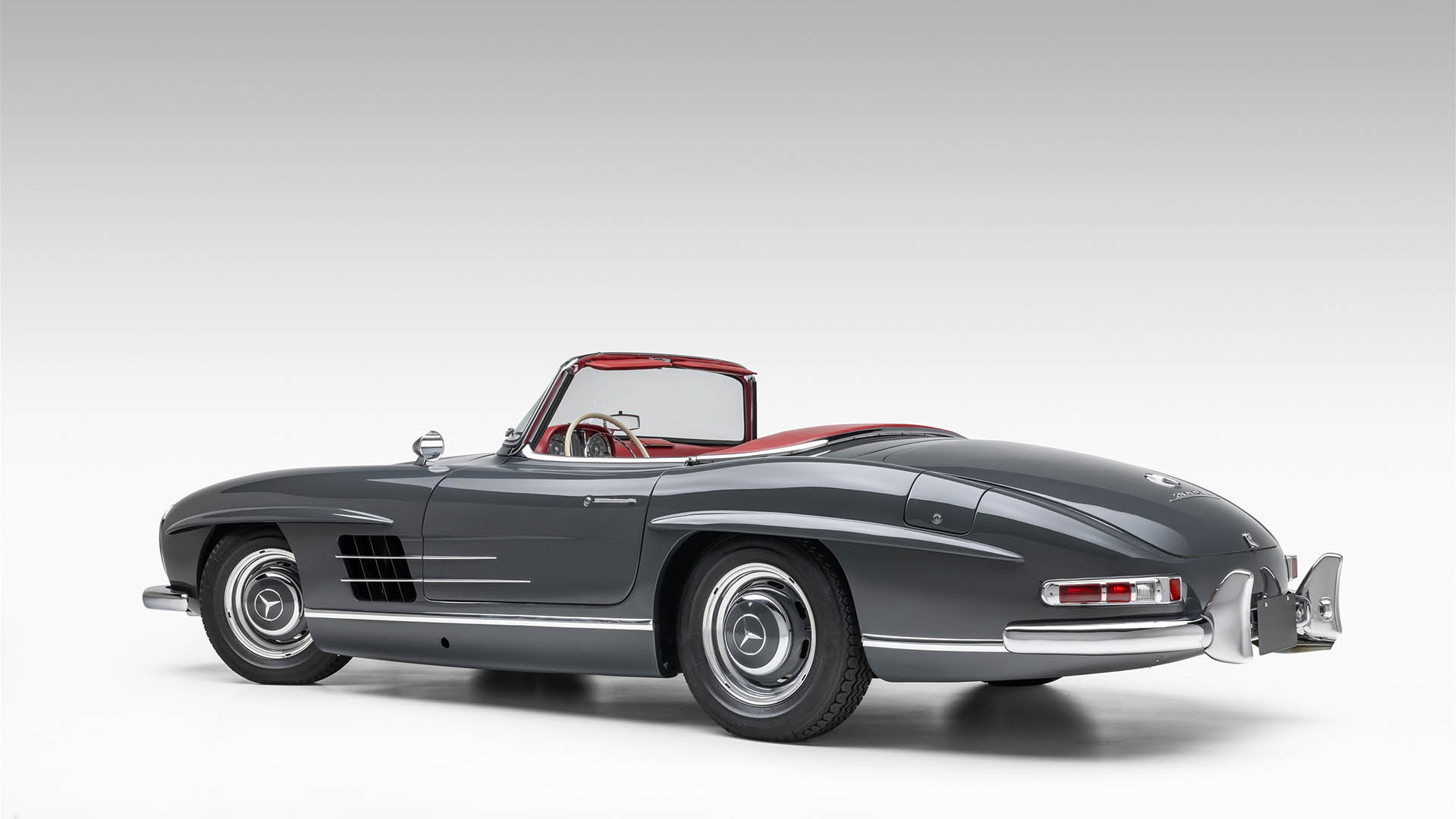 A classic 2009 Mercedes-Benz SLR McLaren convertible with a red interior is shown against a plain white background, viewed from the rear side angle—a highlight for Broad Arrow Las Vegas 2025.