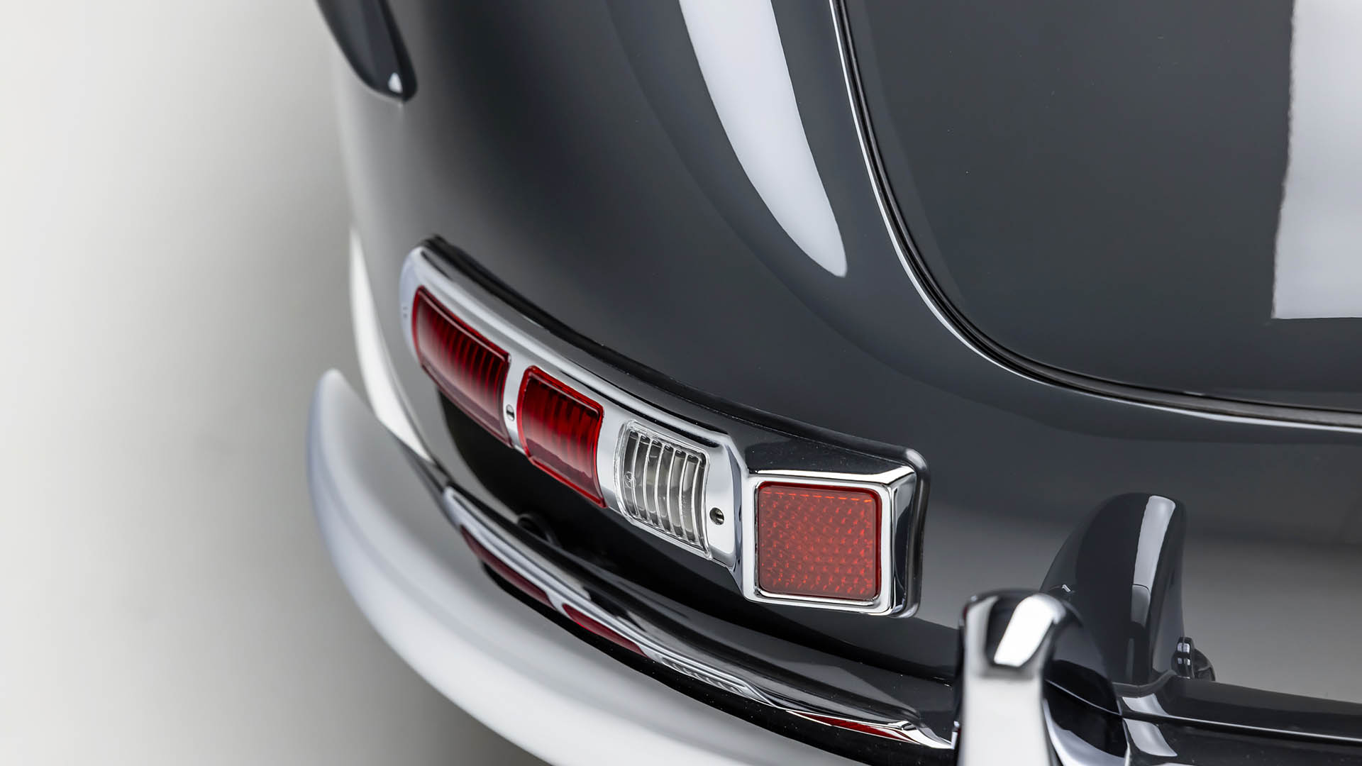 Close-up of the rear tail light assembly and chrome bumper on a classic black Mercedes-Benz SLR McLaren, captured at Broad Arrow Las Vegas.