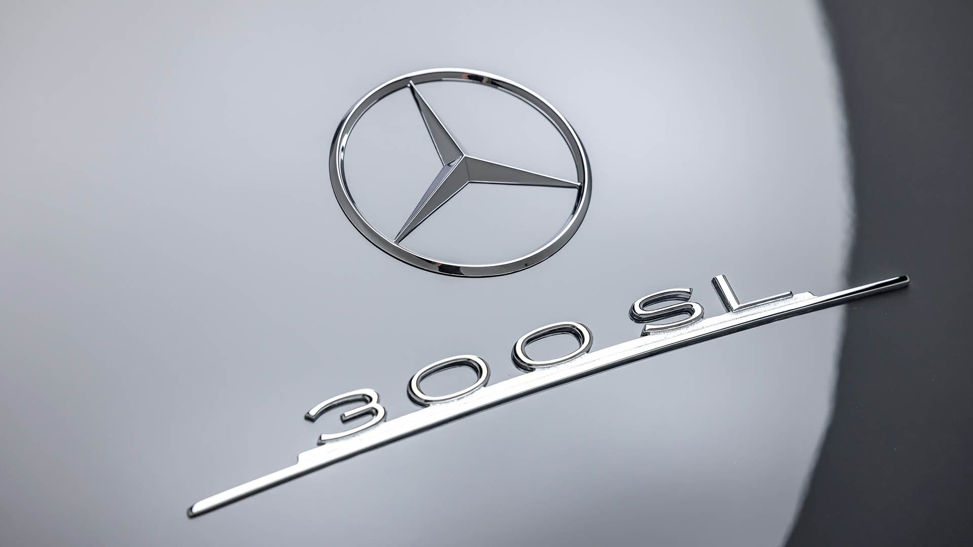 Close-up of the Mercedes-Benz emblem and "300 SL" badge on the curved surface of a classic car, reminiscent of the timeless elegance seen in models like the 2009 Mercedes-Benz SLR. Featured at Broad Arrow Las Vegas 2025.