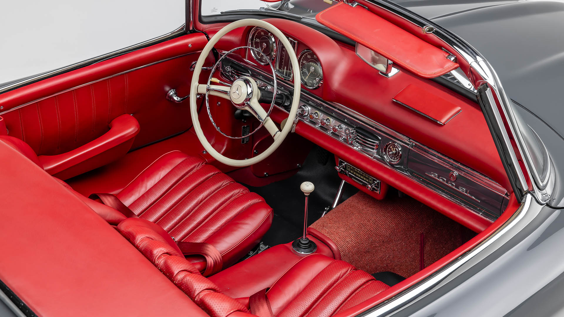 Interior view of a classic convertible car featuring red leather seats, a white steering wheel, and a vintage dashboard with chrome details—perfect for a drive in Las Vegas 2025 or showcasing at Broad Arrow.