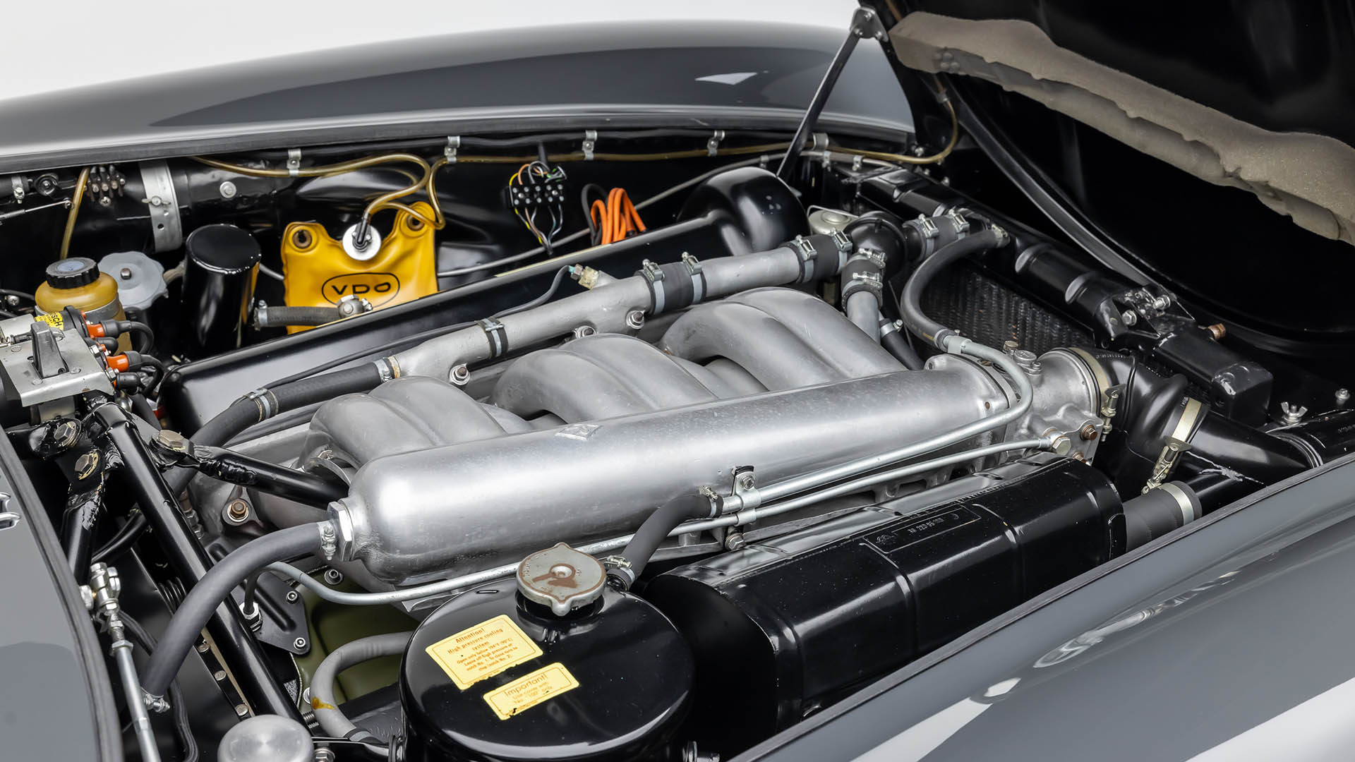 Close-up view of a 2009 Mercedes-Benz SLR engine bay, showcasing detailed mechanical components, cables, and metallic parts with the hood open at Broad Arrow Las Vegas 2025.