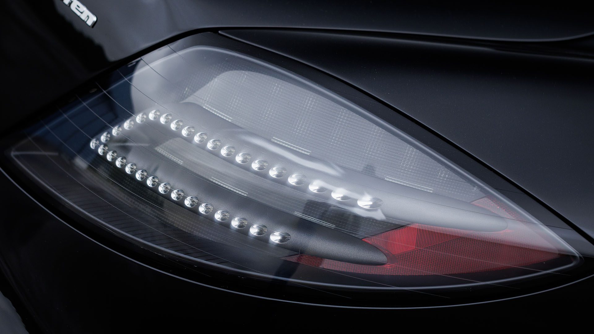 Close-up of a 2010 Bugatti Veyron’s rear tail light with LED elements, encased in a glossy black exterior—an icon set to shine at Broad Arrow Las Vegas 2025.