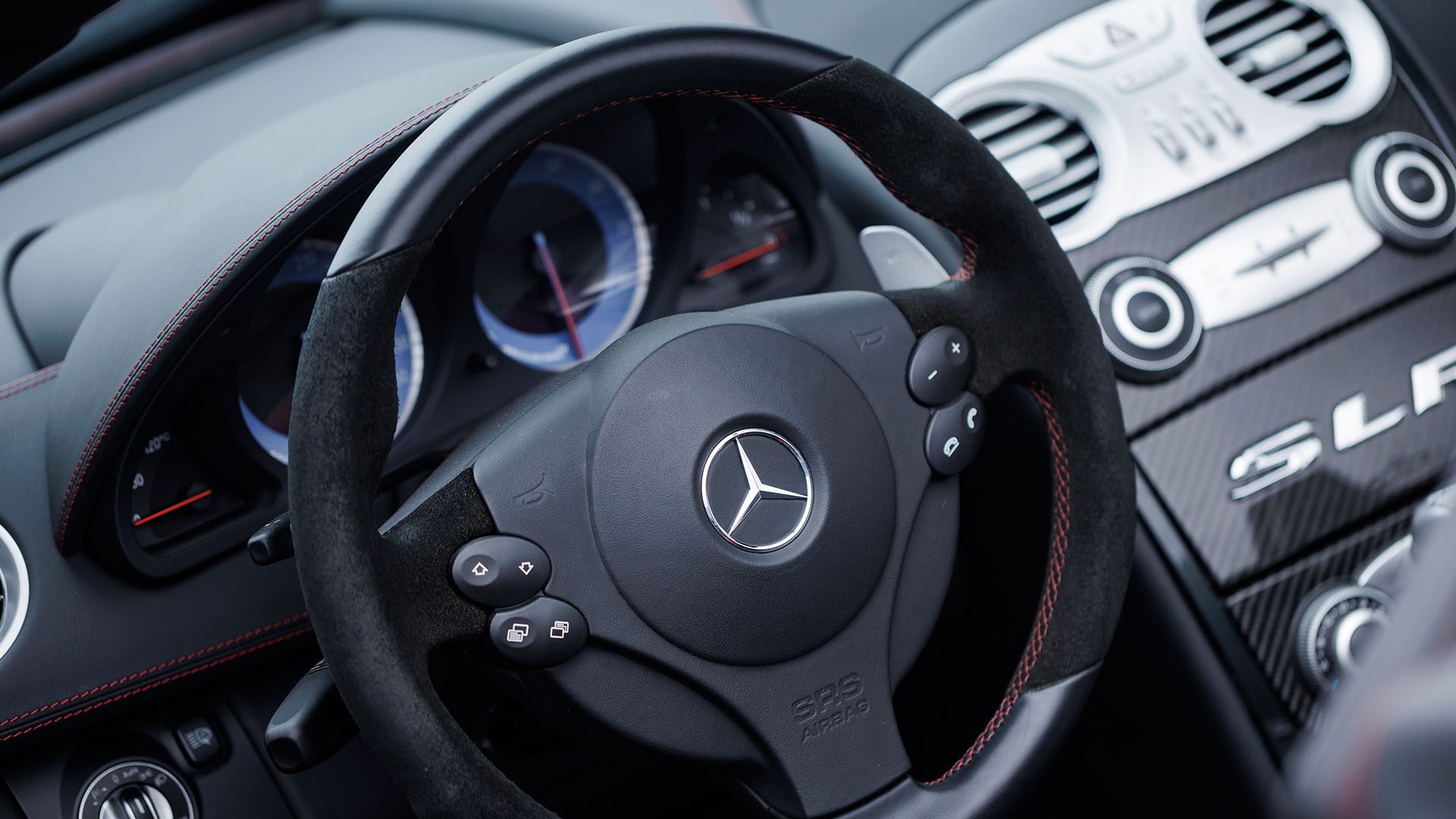 Close-up view of a Mercedes-Benz SLR McLaren steering wheel, dashboard controls, and instrument cluster, reminiscent of luxury interiors seen at events like Broad Arrow Las Vegas 2025.