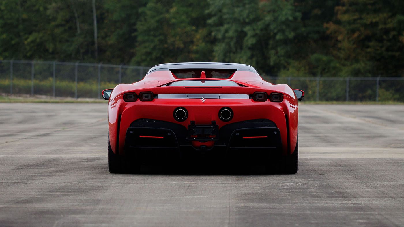 Rear view of a red Bugatti Veyron sports car parked on a paved surface, with trees and a chain-link fence in the background—captured ahead of Broad Arrow’s Las Vegas 2025 event.