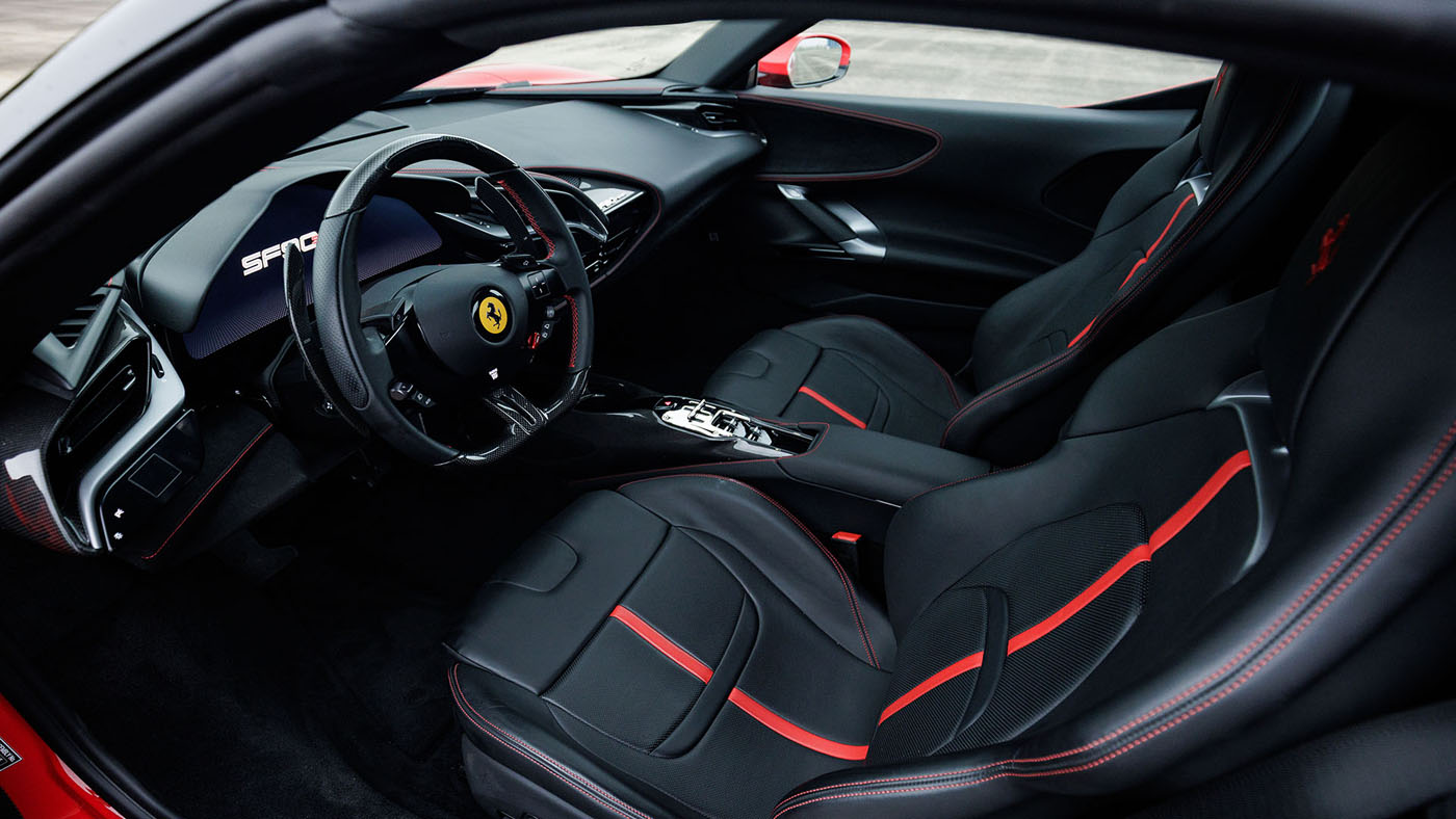 Interior view of a modern sports car with black and red leather seats, a digital dashboard, and a flat-bottom steering wheel featuring the Ferrari logo—capturing the excitement of Broad Arrow’s Las Vegas 2025 auction.
