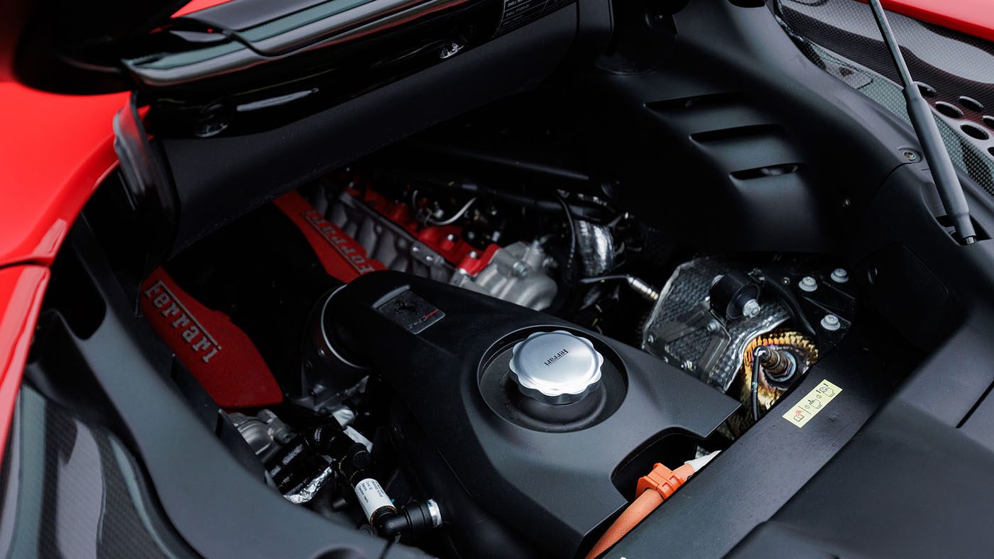 Close-up view of a Ferrari engine bay, showcasing engine components and red valve cover with Ferrari branding—true automotive artistry, rivaling the engineering perfection found in the 2010 Bugatti Veyron.