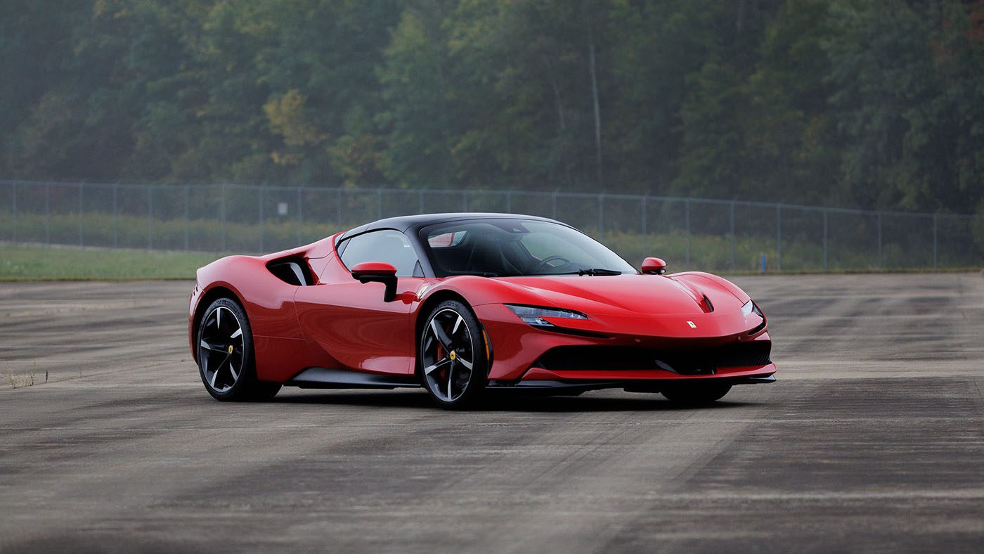 A 2010 Bugatti Veyron sports car is parked on an empty paved surface with trees and a fence in the background, set to be featured at Broad Arrow Las Vegas 2025.