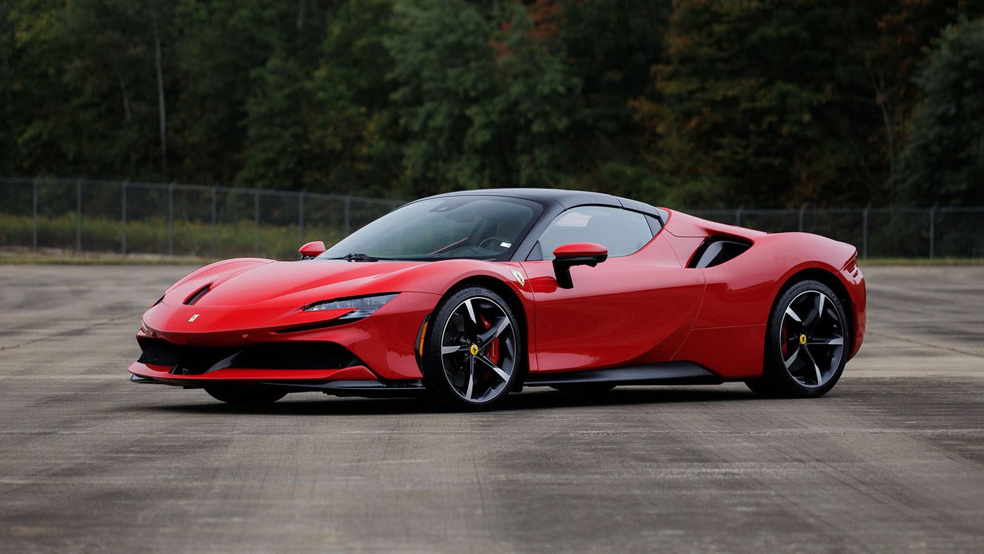 A 2010 Bugatti Veyron sports car is parked on a paved surface with a fence and trees in the background, set to appear at Broad Arrow Las Vegas 2025.