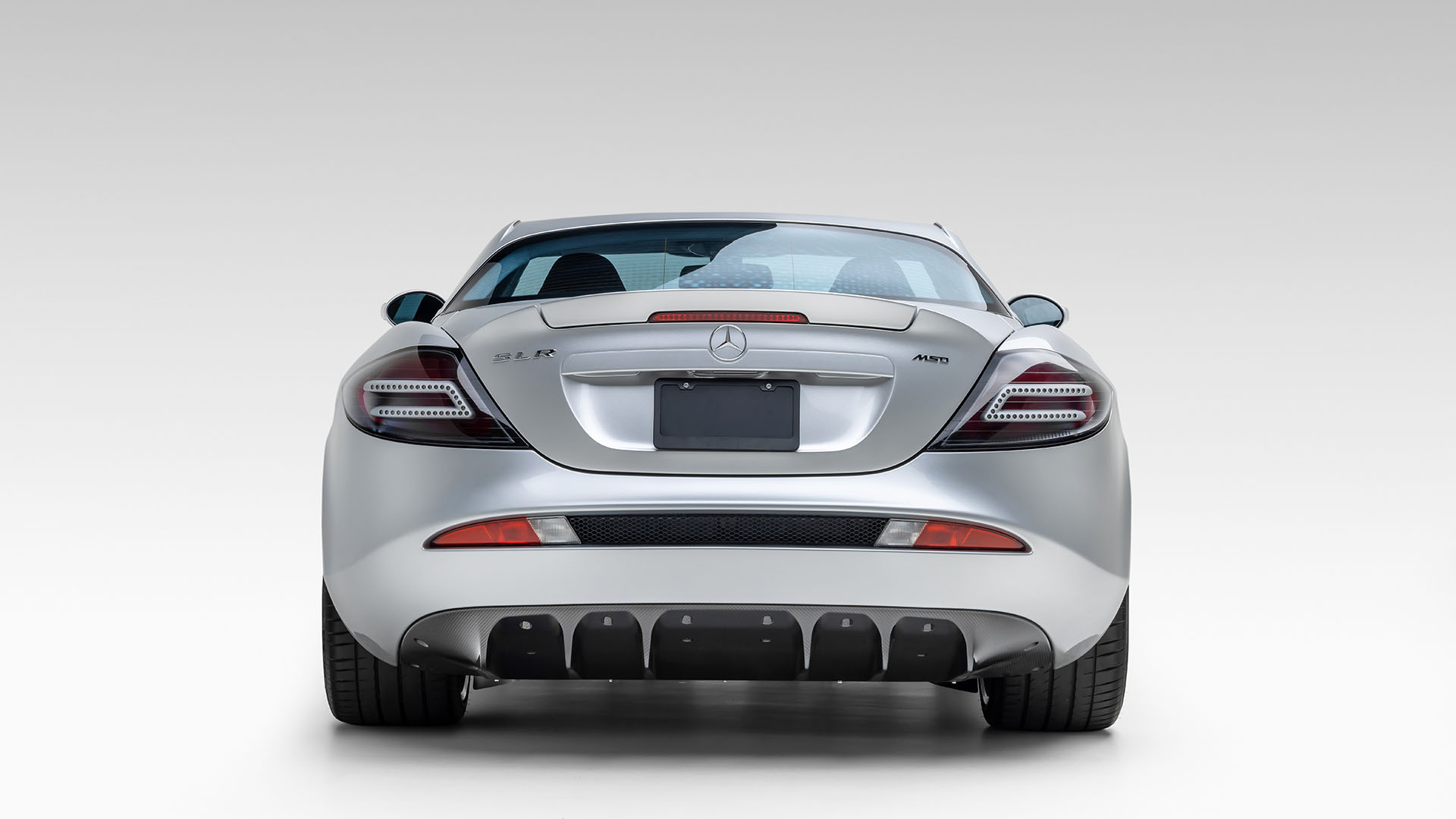 Rear view of a silver Mercedes-Benz SLR McLaren sports car against a plain white background, reminiscent of classic icons like the 1962 Mercedes-Benz 300 SL Roadster and perfect for a premier car auction such as Broad Arrow Las Vegas 2025.