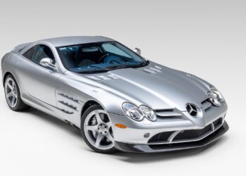 A silver Mercedes-Benz SLR McLaren coupe is parked in a studio with a plain white background, reminiscent of the elegance seen at Broad Arrow’s Las Vegas 2025 event.