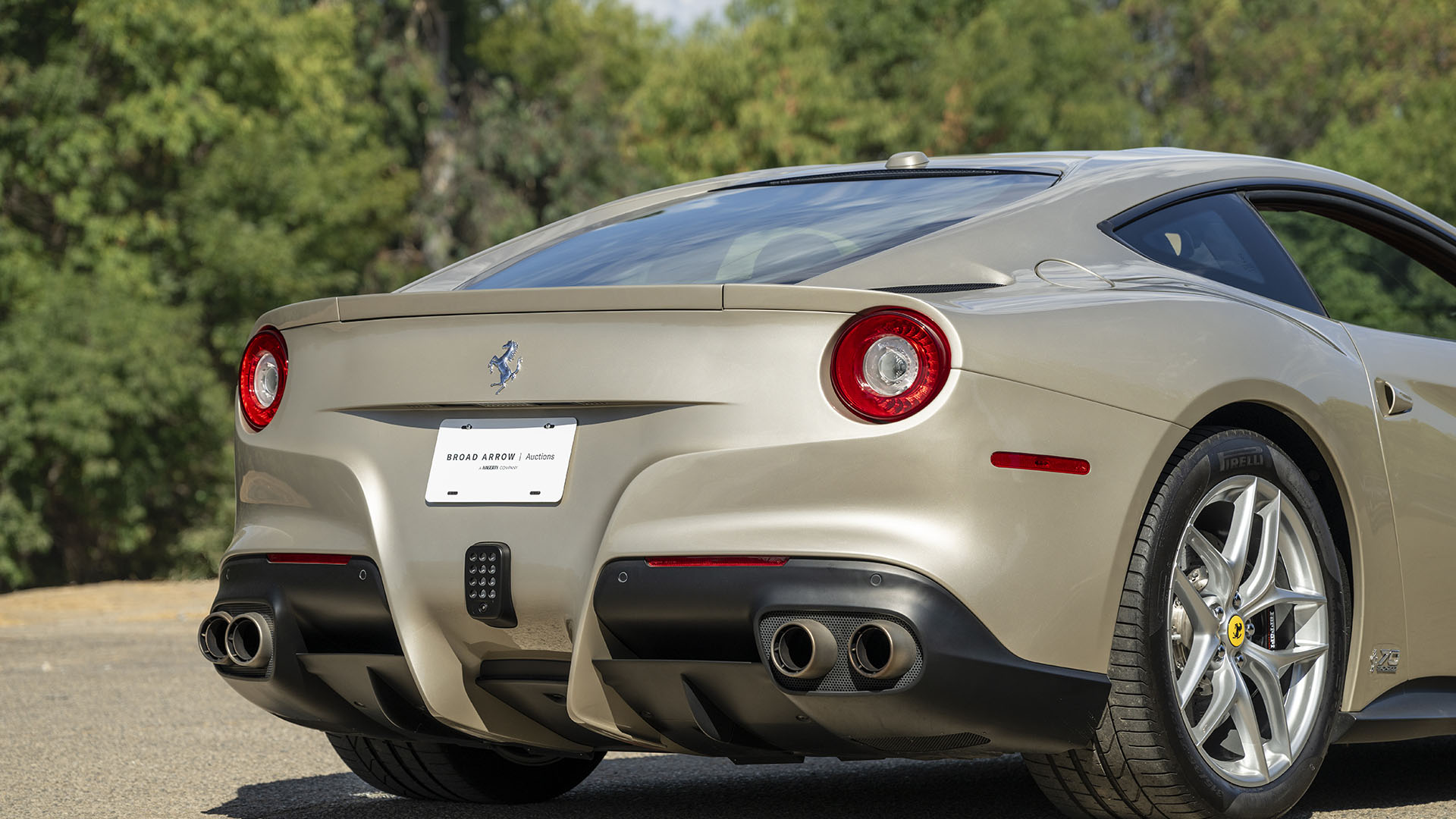 Sidabrinio Ferrari F12berlinetta 70th Anniversary Edition, pastatyto lauke 2025 m. Las Vegase, vaizdas iš galo, kuriame demonstruojami galiniai žibintai, keturių išmetimo vamzdžiai ir galinis difuzorius.