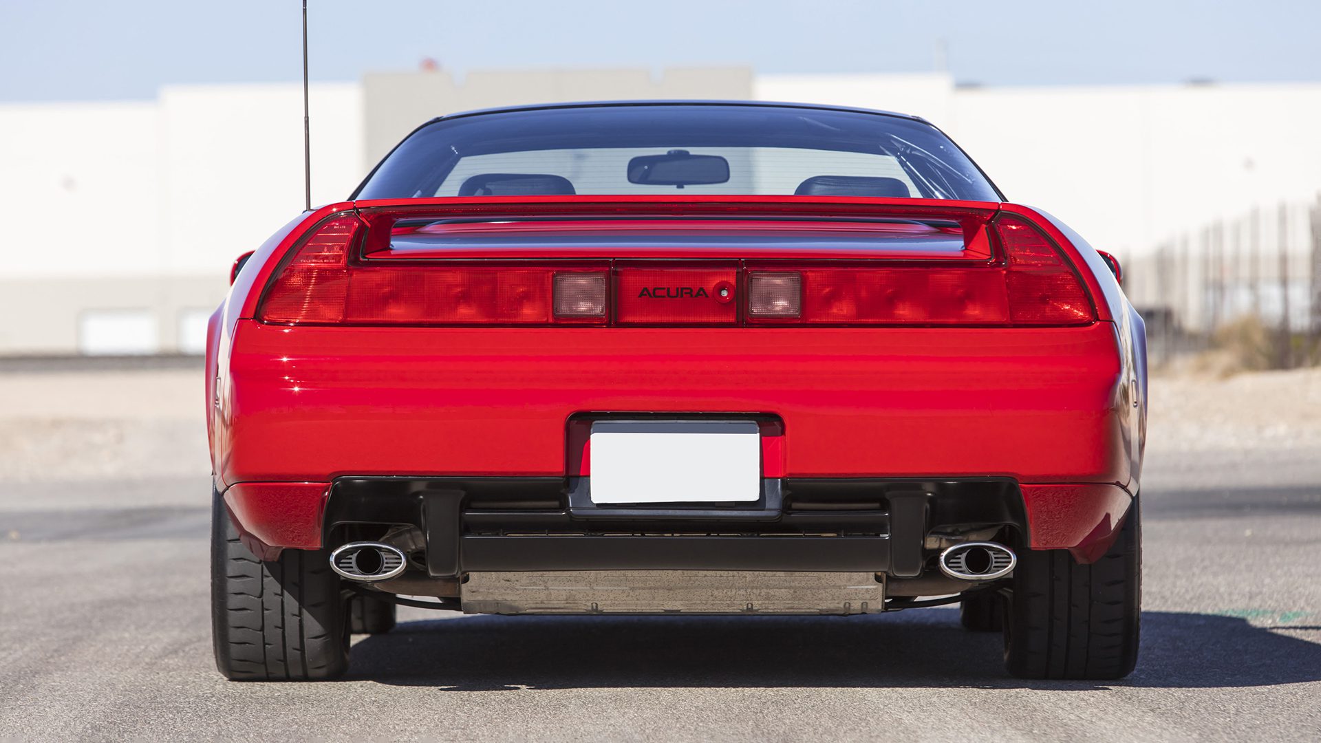 Rear view of a red Acura NSX sports car parked on a road, showing dual exhaust pipes and a spoiler—capturing excitement similar to the Ferrari SF90 Spider at the Broad Arrow Las Vegas 2025 Preview.