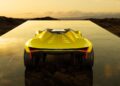 A yellow sports car with angular design—showcasing how Centro Stile is shaping the future of Lamborghini design—is parked on a reflective platform, with rocky terrain and a sunset sky in the background.