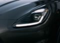 Close-up view of the Maserati Grecale Folgore EV’s sleek headlight and glossy dark-painted hood, showcasing LED light detailing and smooth vehicle contours.