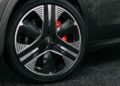 Close-up of a Maserati Grecale Folgore's black and silver alloy wheel, featuring advanced EV Tech, with a visible Maserati logo and red brake caliper on dark asphalt.