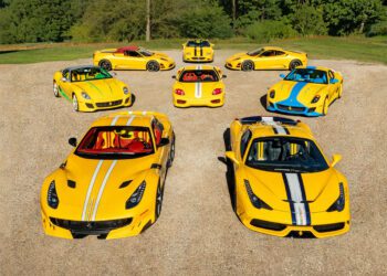 Eight yellow Ferrari sports cars with white and blue racing stripes, part of exclusive Ferrari Collections, are arranged in a semicircle on a gravel surface, with trees and grass in the background.