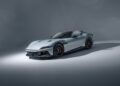 A silver Ferrari sports car is parked on a plain, light-gray studio background, shown from a front three-quarter angle.