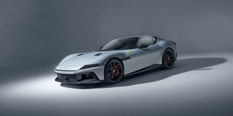 A silver Ferrari sports car is parked on a plain, light-gray studio background, shown from a front three-quarter angle.