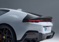 Rear view of a white Ferrari 12Cilindri sports car featuring customizations like black wheels, quad exhaust pipes, and a license plate reading "MN F1," with striking tail lights, shown against a plain background.