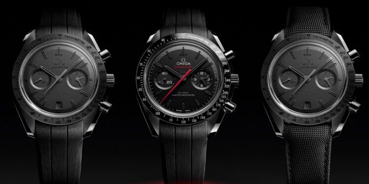 Three black Omega Speedmaster chronograph watches are displayed side by side against a dark background, with the center watch featuring a red second hand.
